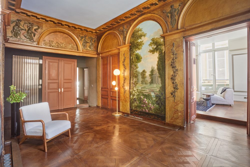 Entrée principale de l'appartement Thérèse avec boiseries d'époque, fresques et mobiliers design.